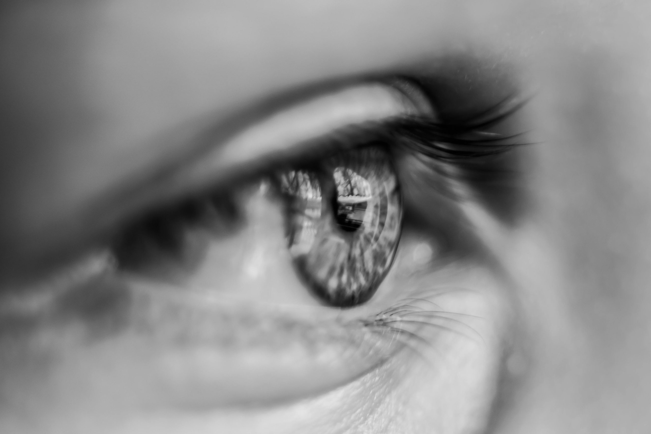 Artistic close-up of a human eye in monochrome, showcasing detail and reflection.